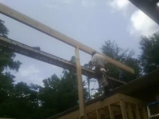 Carpenter setting a ridge beam over a new addition frame — Ice Dam Removal by Roofing Brothers in Purcell