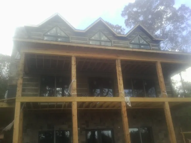 Dormers and porch framing on a large log home under construction — Roof Coating work by our crew in Purcell