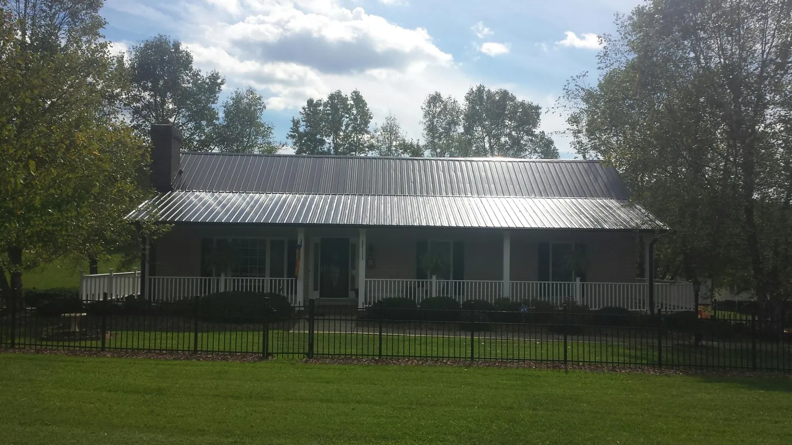 Gray metal roof on a brick ranch with a full width front porch — Gutter Guard Installation work by our crew in Purcell