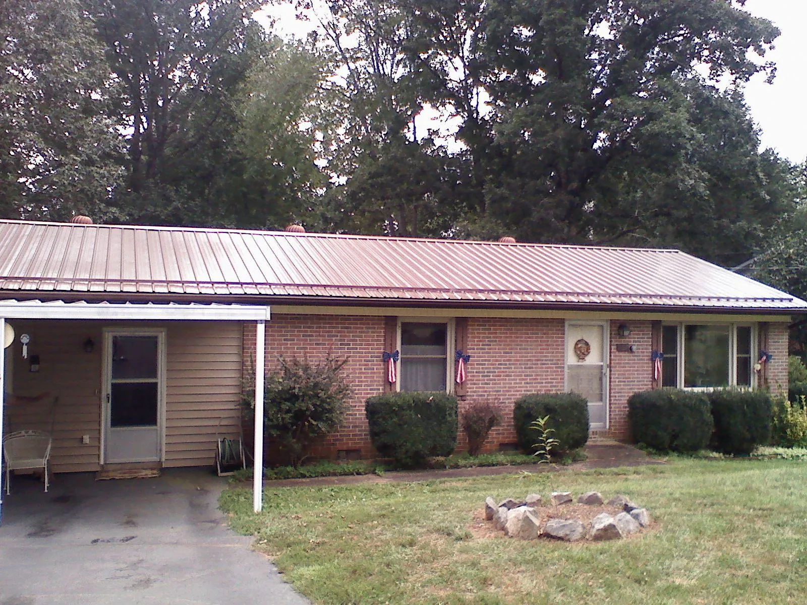Bronze metal roof and carport on a brick ranch home — Roof Repair work by our crew in Purcell