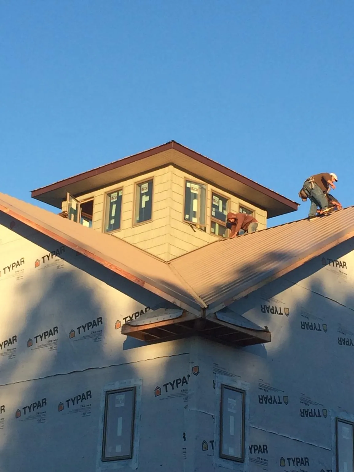 Roofers working around a rooftop cupola on a new metal roof at sunset — Roof Waterproofing in Purcell by Roofing Brothers